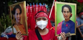 A supporter of National League for Democracy (NLD) holds two portraits of Myanmar State Counselor Aung San Suu Kyi | Licas News