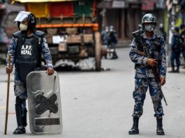 BI_Riot police stand guard on a street during a curfew
