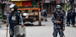 BI_Riot police stand guard on a street during a curfew