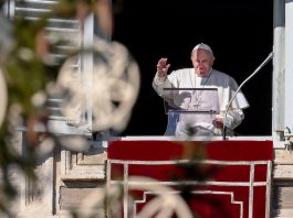 Pope Francis waves from apostolic palace overlooking St. Peter's Square during the weekly Angelus prayer on Dec. 13, in the Vatican.