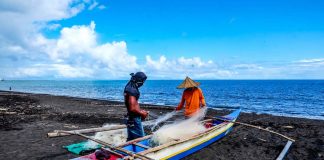 Fishermen fix their nets on the shore