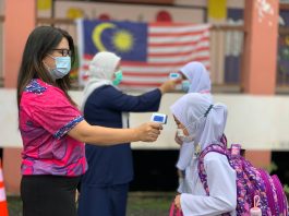 Students have their temperature taken at a school in Malaysia