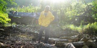 A man stands on the ground where he burned wood and excavated soil to make charcoal