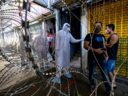 Malaysian health worker in PPE behind barbed wire fence | LiCAS.news