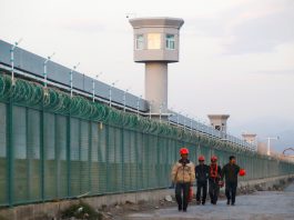 Workers walk by the perimeter fence in Xinjiang