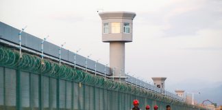 Workers walk by the perimeter fence in Xinjiang