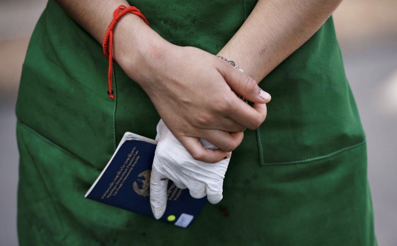 Nurse in green overall holding blue passport