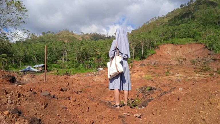 A nun standing among cyclone desvasted landscape | LiCAS.news