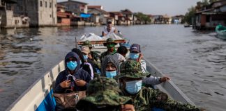 Government workers and policemen ride a boat to the island of Tibaguin, Philippines