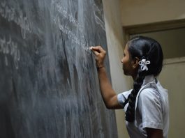 Indian girl writing on blackboard with chalk