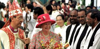 Queen Elizabeth II​ holding a bouquet of flowers while meeting priests in Malaysia