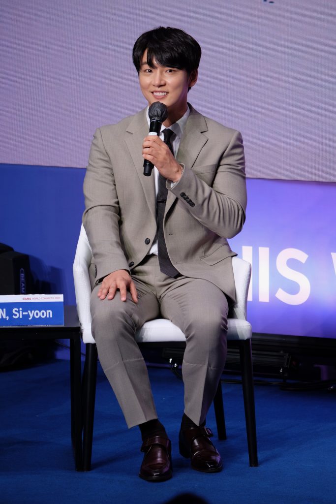 Actor Yoon Si-Yoon 윤시윤 speaking on stage while sitting wearing a gray suit