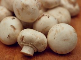 A pile of button mushrooms on wooden surface