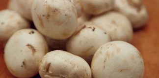 A pile of button mushrooms on wooden surface