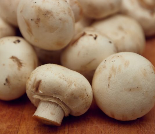 A pile of button mushrooms on wooden surface