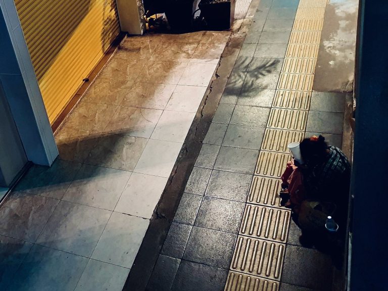 A beggar on an empty pavement in Bangkok, Thailand
