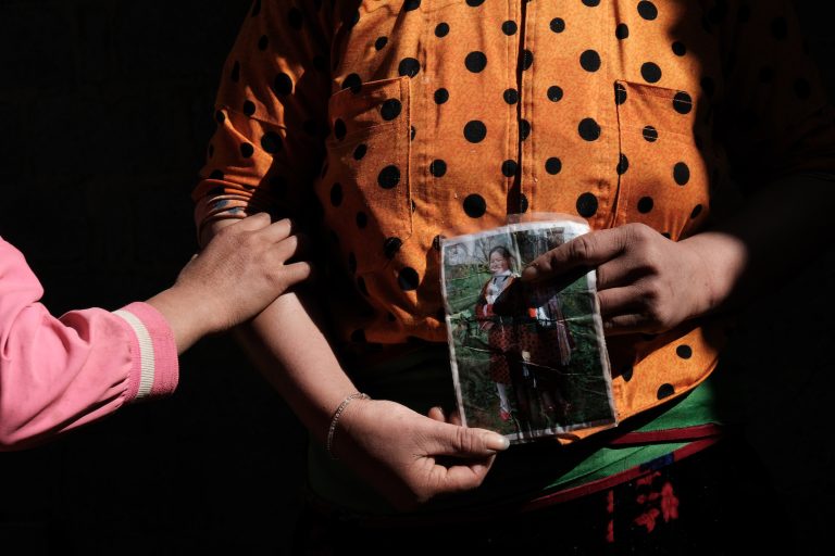 Close up photo of a Vietnamese mother holding a photo of her missing daughter