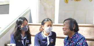 Two female high school students talking with a female bread seller in Thailand