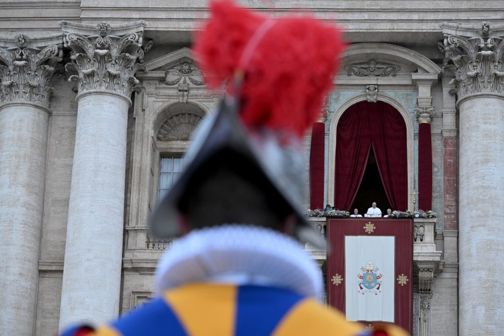 Swiss guard in blurry foreground with Pope Francis in focus in the background