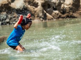 A girl splashes joyfully in shallow river water