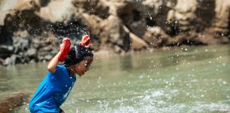 A girl splashes joyfully in shallow river water