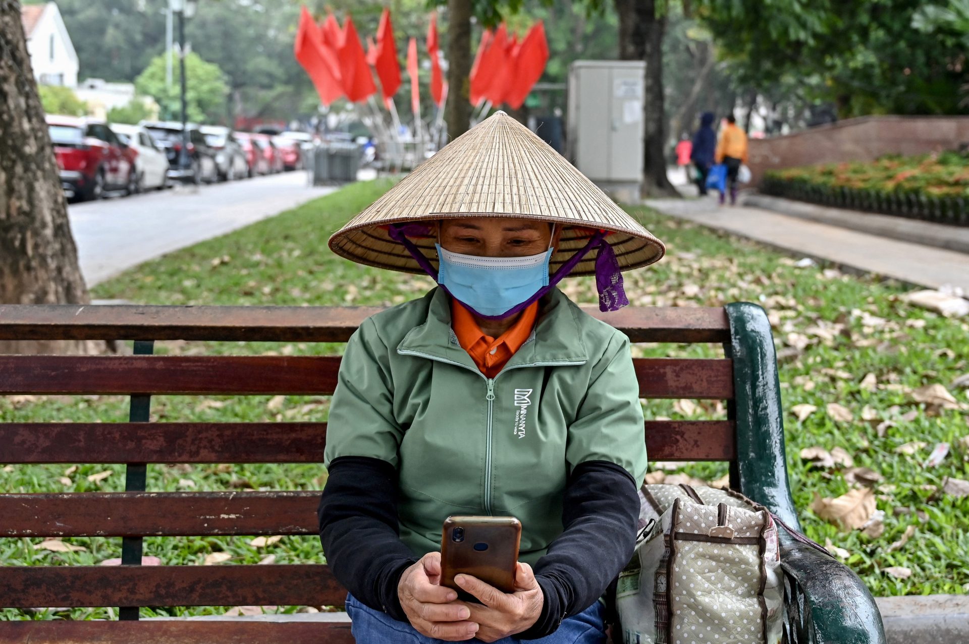 A worker uses a smartphone at a park in Hanoi