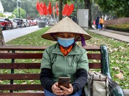 A worker uses a smartphone at a park in Hanoi