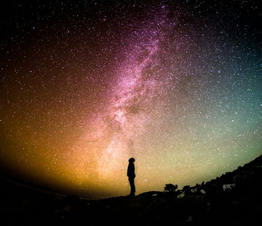 A human standing looking up at the Milky Way.