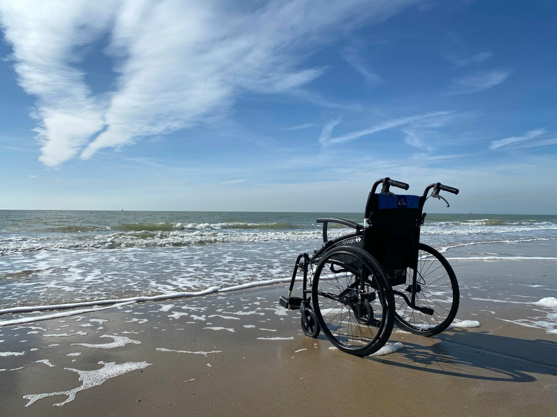 An empty wheelchair on a sandy beach on a sunny day