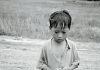 Black and white photo of a poor boy in rural setting in Asia