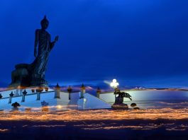 Visakha Bucha Day procession at Buddha Monthon in Nakhon Pathom, Thailand, with candle streaks against the dark blue evening sky
