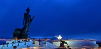 Visakha Bucha Day procession at Buddha Monthon in Nakhon Pathom, Thailand, with candle streaks against the dark blue evening sky