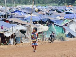 A young boy walks past rows of makeshift tents at a refugee camp near the Cambodia–Thailand border.