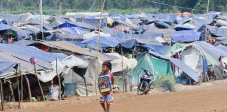 A young boy walks past rows of makeshift tents at a refugee camp near the Cambodia–Thailand border.